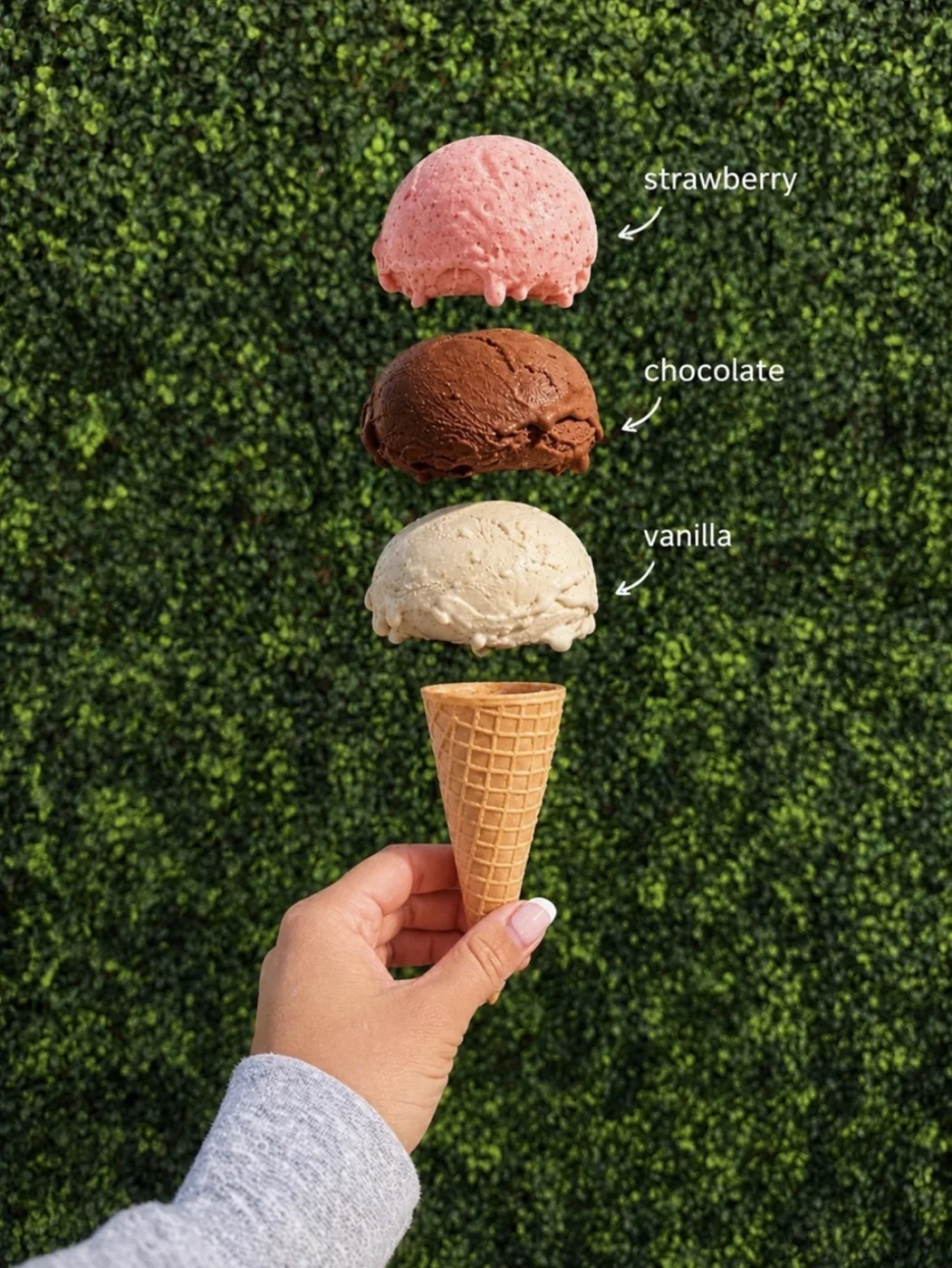 Vanilla, chocolate and strawberry scoops stacked above a cone